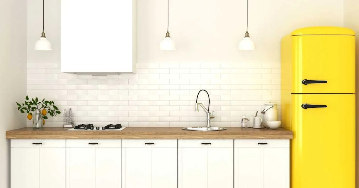 آشپزخانه با کابینتهای سفید و بینکابینتی آجری سفید و یخچال زرد