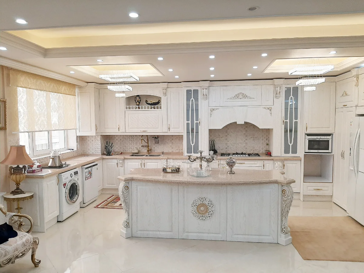 کابینت و جزیره کلاسیک سفید ممبران با منبتکاریهای طلایی همراه با درب ویترینی