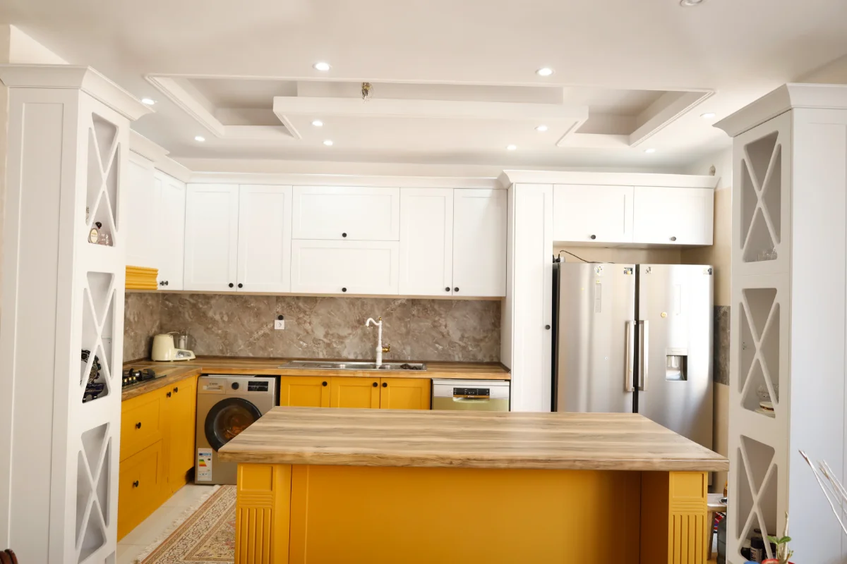 کابینت نئوکلاسیک ممبران سفید خردلی با دستگیرههای دکمهای مشکی و کابینت ویترینی و کمدی