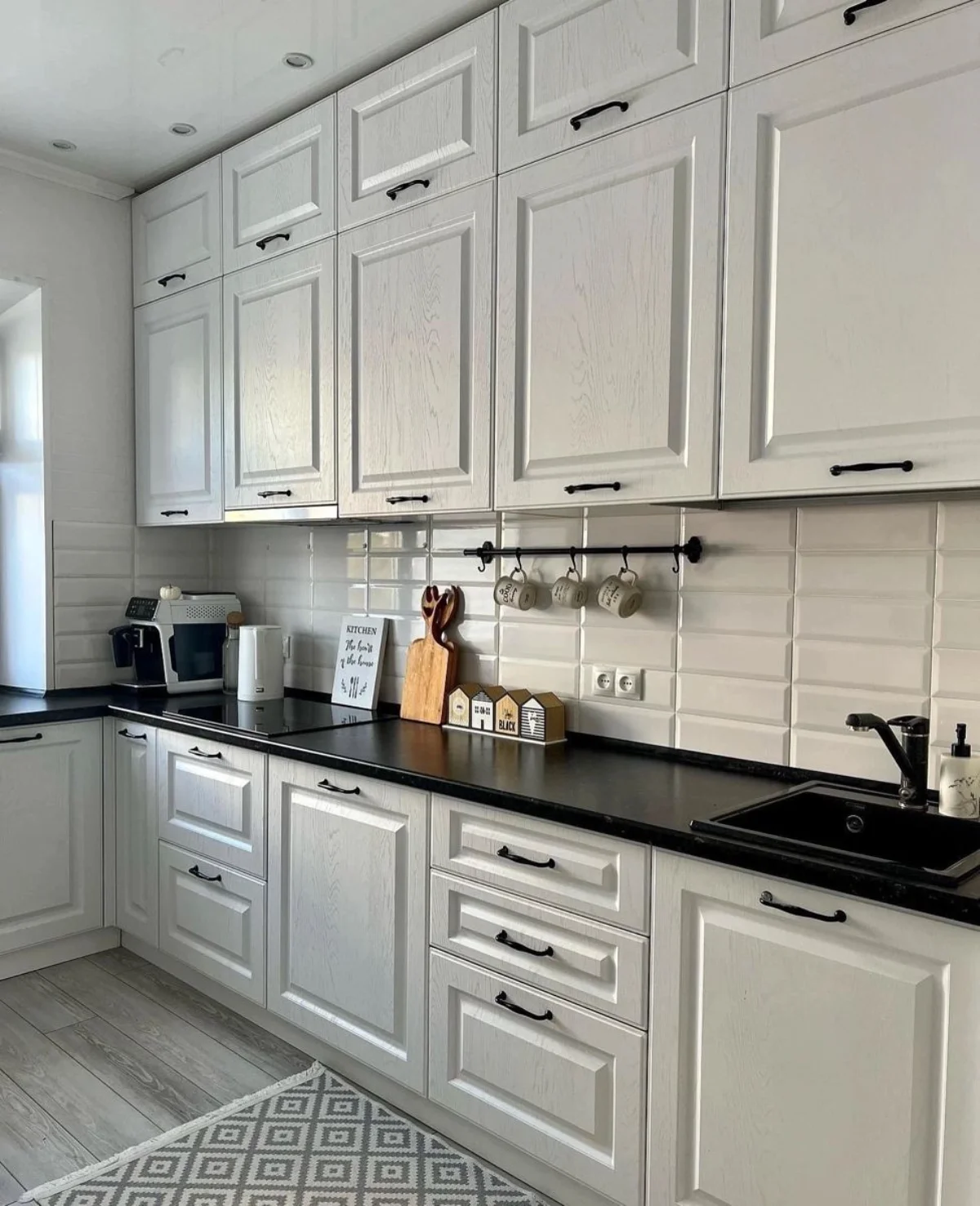 کابینت نئوکلاسیک سفید با صفحه کابینت و دستگیرههای مشکی و چندین کشو در یونیتهای زمینی