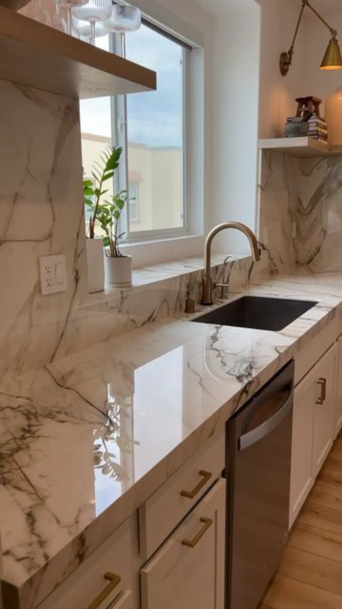 صفحه کابینت سه سانتی و صفحه بین کابینتی همرنگ با طرح سنگ و رگههای طوسی و سینک زیر پنجره