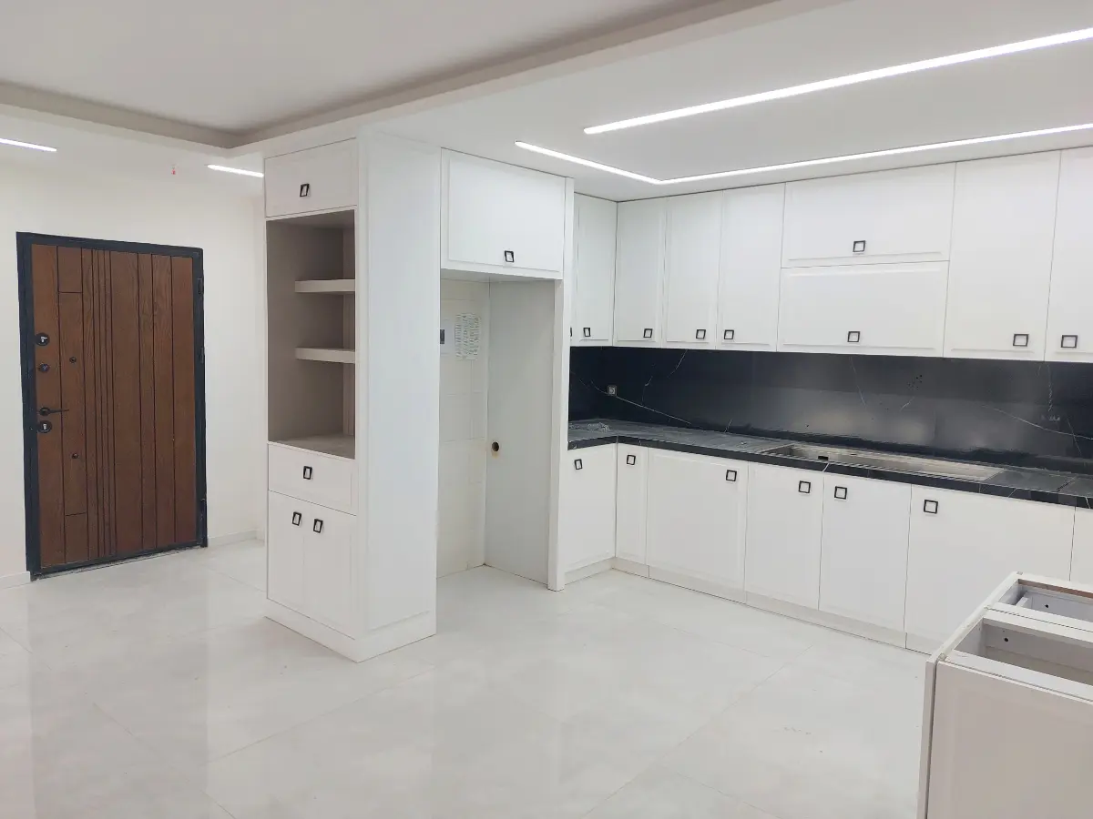 کابینت پولیشی سفید با دستگیرههای مربعی شکل و کافی بار بژ مشرف به پذیرایی