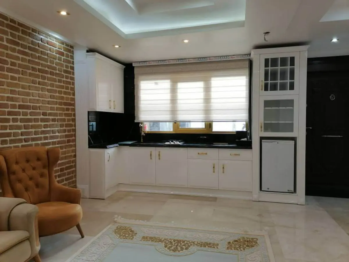 کابینت سفید با دستگیره طلایی و صفحه کابینت و بینکابینتی سنگ مشکی
