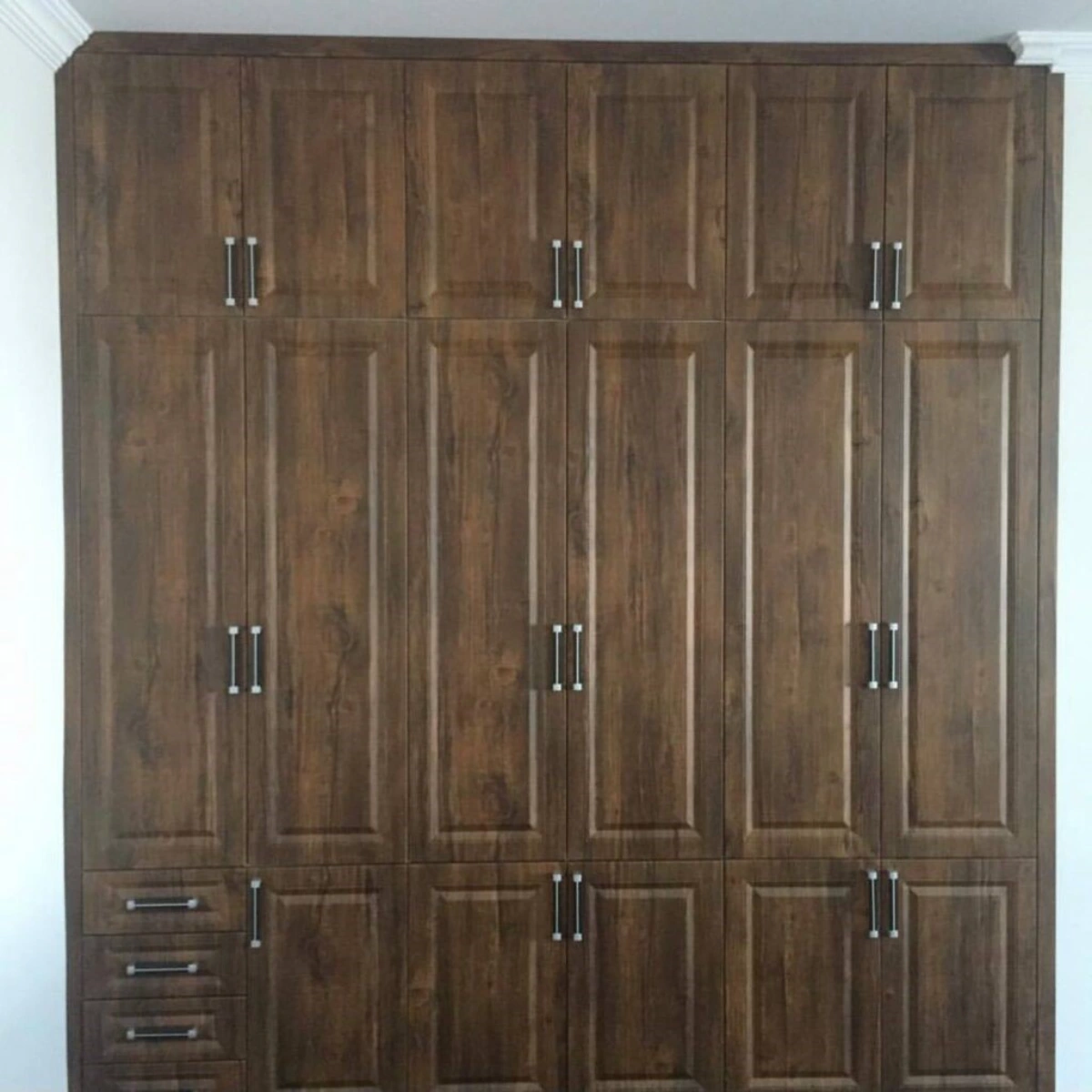 کمد دیواری ممبران طرح چوب به رنگ قهوه ای تیره با دستگیره مشکی نقره ای و دارای کشو