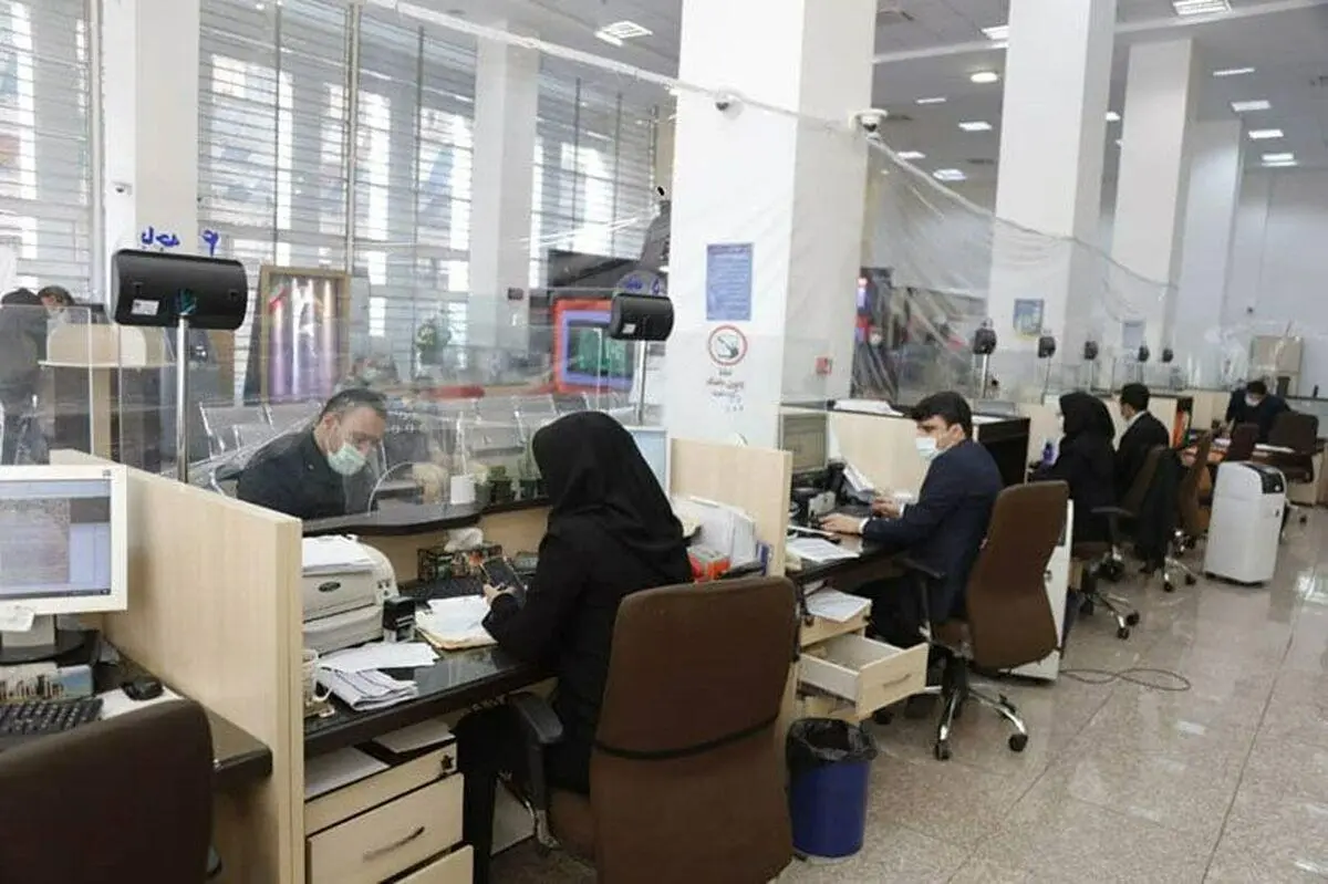 فضای کار کارمندان بانک همراه با کامپیوتر، صندلی قهوهای و میز چوبی