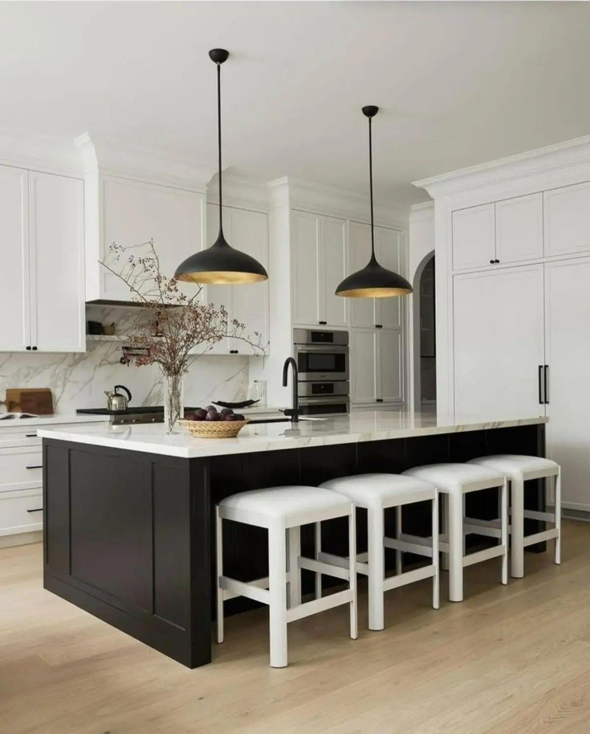 کابینت نئوکلاسیک سفید با دستگیره مشکی همراه با جزیره مشکی و صندلیهای سفید